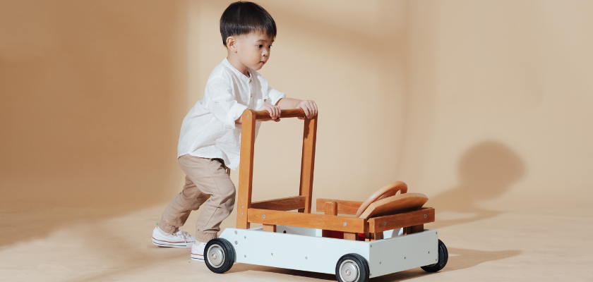 Otrok ki se igra z lesenim vozičekom. 